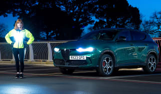 Auto Express pictures editor Dawn Grant standing next to the Alfa Romeo Tonale PHEV at night